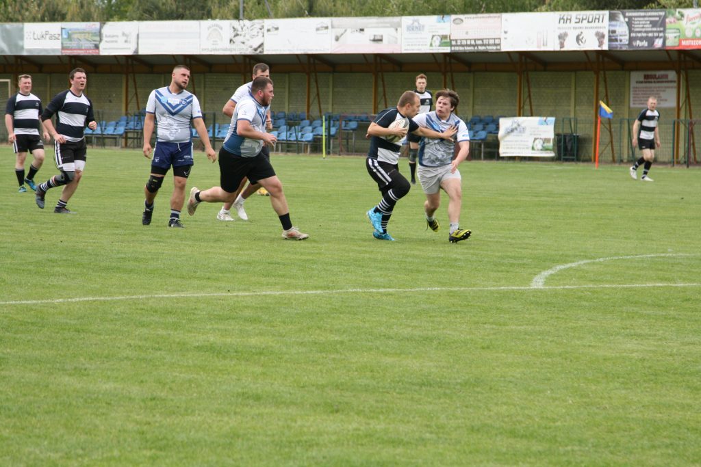 Rugbysta z piłką pokonuje obronę przeciwnika